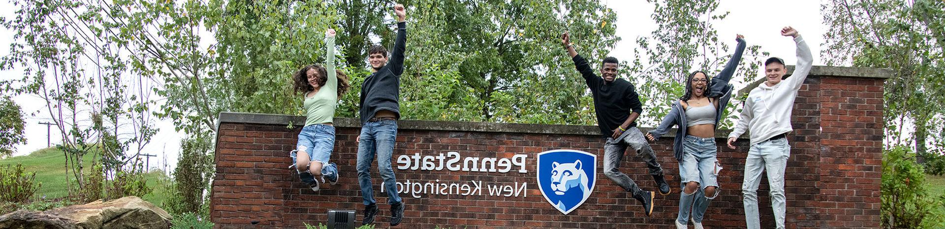 Student jumping in front of the New Kensington sign. 